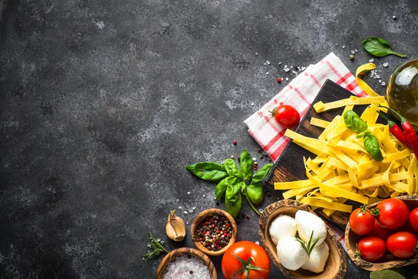 Pasta, tomaten, kaas, basilicum en olijfolie op zwarte stenen tabl — Stockfoto