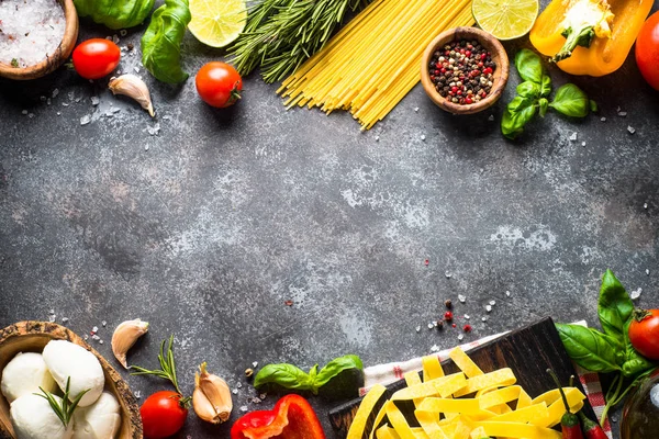 Olasz élelmiszer-háttér. Tészta, gyógynövények, zöldségek, fekete felső v — Stock Fotó