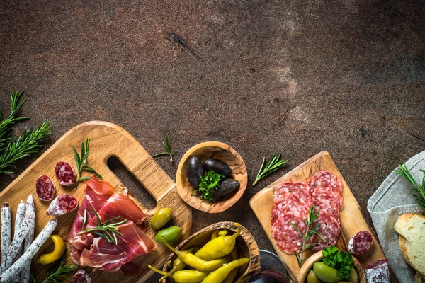 Antipasto - sliced meat, ham, salami, olives on dark stone table — Stock Photo, Image