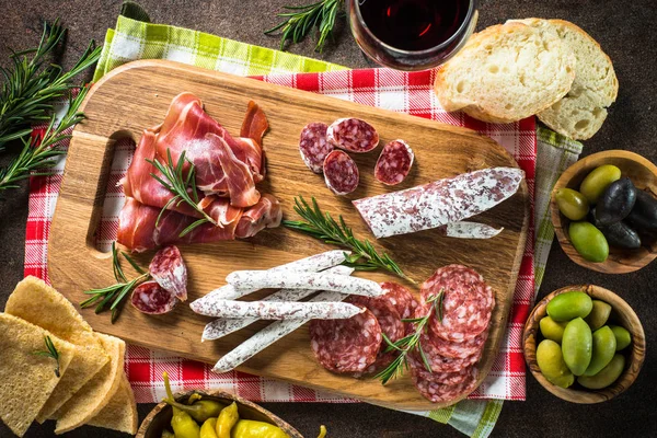 Antipasti - nakrájené maso, šunka, salám, olivy na temný kamenný stůl — Stock fotografie