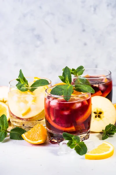 White, pink and red sangria with fruit, ice and mint.