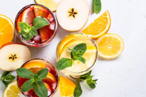 White, pink and red sangria with fruit, ice and mint top view.