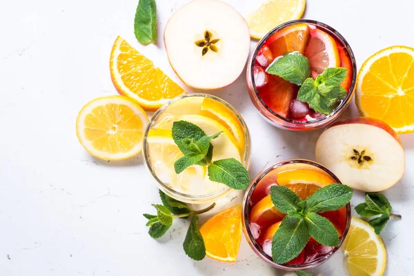 White, pink and red sangria with fruit, ice and mint top view.