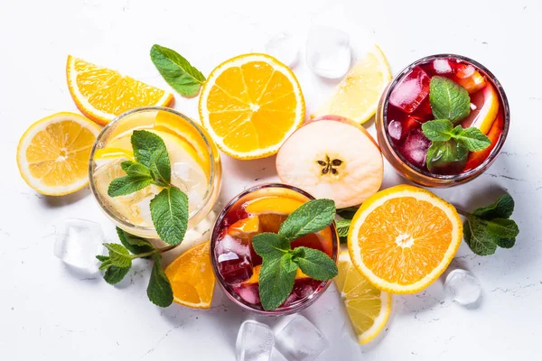 White, pink and red sangria with fruit, ice and mint top view.