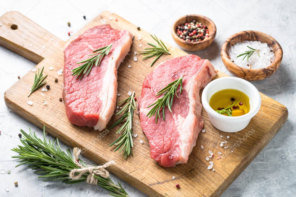 Raw beef striploin steak on cutting board. 