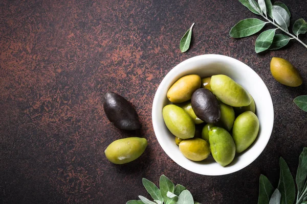 Olijven en olijfolie op donkere stenen tafelblad bekijken. — Stockfoto