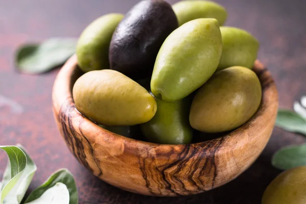 Olivy a olivový olej na temný kamenný stůl. — Stock fotografie