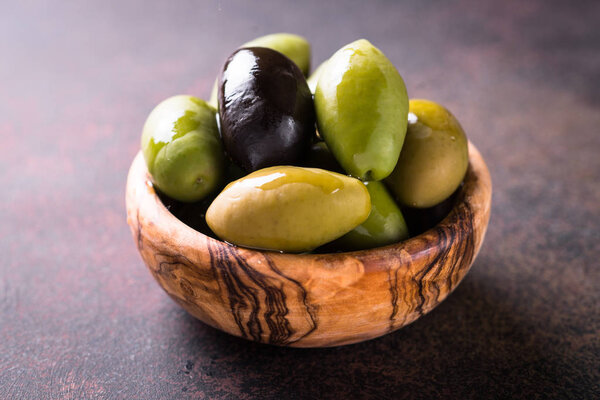 Olives and olive oil on dark stone table.