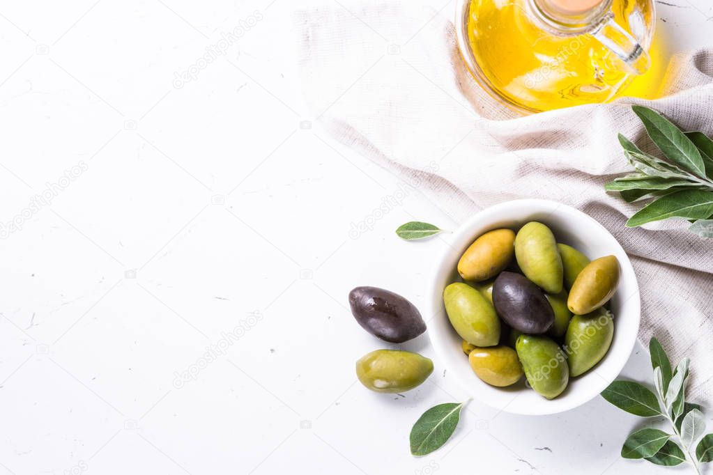 Olives and olive oil on white.