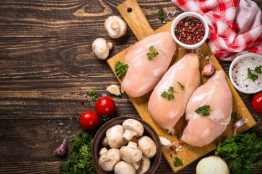 Ahşap masada yemek pişirmek için malzemeli tavuk fileto..