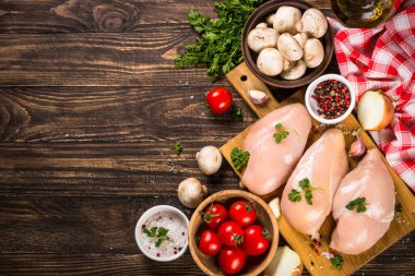 Ahşap masada yemek pişirmek için malzemeli tavuk fileto..