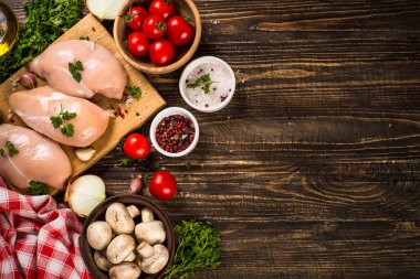 Ahşap masada yemek pişirmek için malzemeli tavuk fileto..