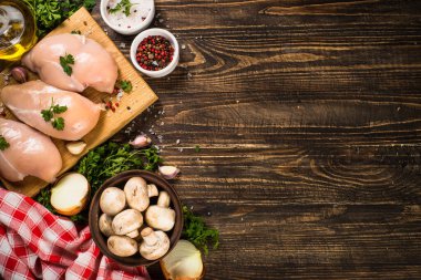 Ahşap masada yemek pişirmek için malzemeli tavuk fileto..