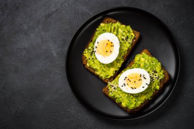 Siyah arkaplanda Avokado Sandviçleri.