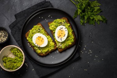 Siyah arkaplanda Avokado Sandviçleri.