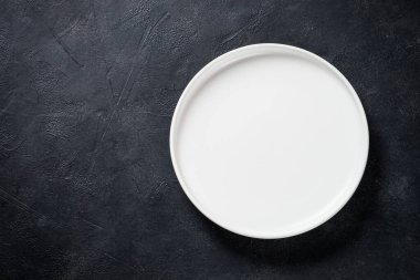 Siyah masa manzaralı beyaz tabak, çatal bıçak ve peçete..