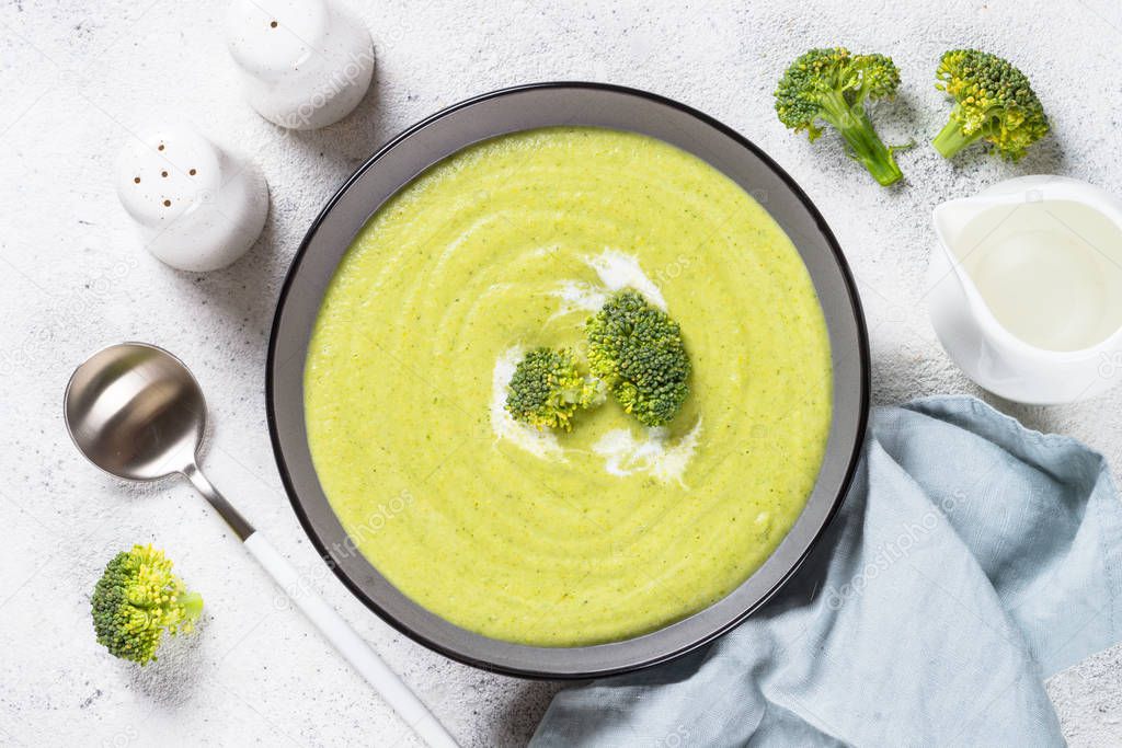 Broccoli cream soup in the bowl on white table.