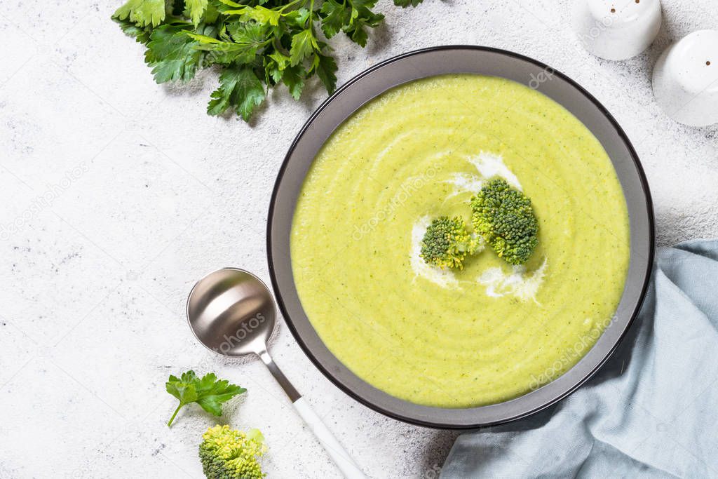 Broccoli cream soup in the bowl on white table.