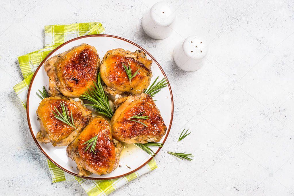 Baked chicken thighs with herbs on white plate.
