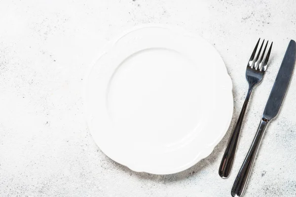 Белая тарелка и столовые приборы на белом фоне . — стоковое фото
