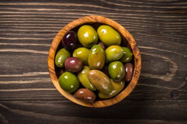 Black and green olives on wooden table. clipart