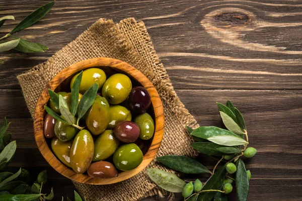 Черные и зеленые оливки на деревянном столе. — стоковое фото