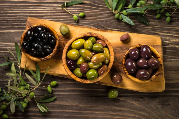 Black and green olives on wooden table. — Stock Photo, Image