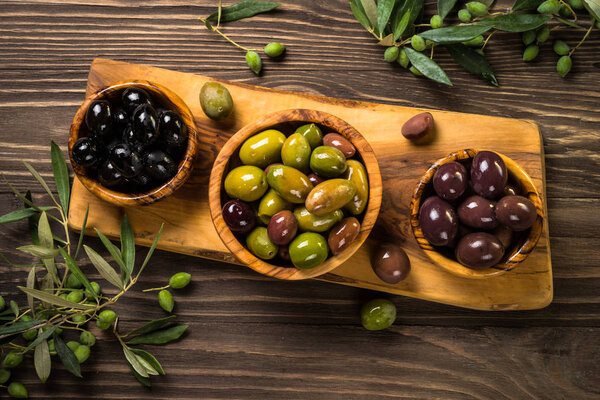 Black and green olives on wooden table.