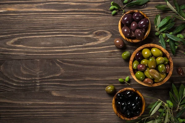 Aceitunas negras y verdes sobre mesa de madera. —  Fotos de Stock