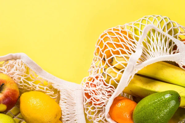 Netztasche mit Früchten auf farbigem Hintergrund. — Stockfoto