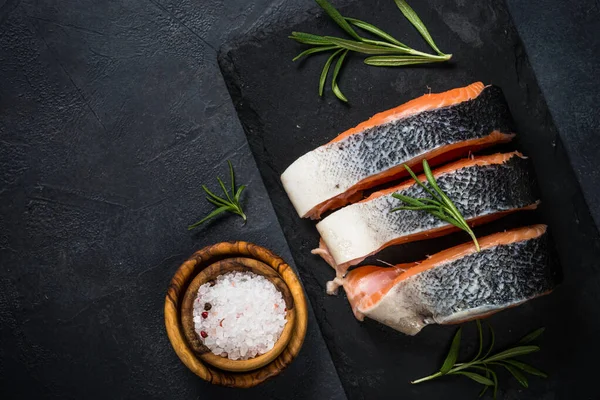 Rauwe zalmsteak op zwart bovenaanzicht. — Stockfoto