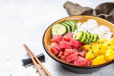 Beyaz masada pirinç, avokado, mango ve salatalık ile tuna poke kase.