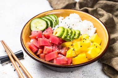 Beyaz masada pirinç, avokado, mango ve salatalık ile tuna poke kase.