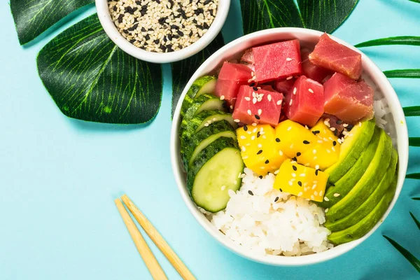 Thunfisch-Poke-Schüssel mit Reis, Avocado, Mango und Gurke auf blau. — Stockfoto