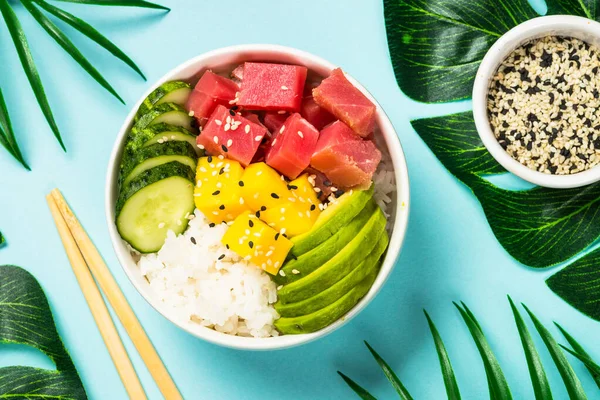 Thunfisch-Poke-Schüssel mit Reis, Avocado, Mango und Gurke auf blau. — Stockfoto