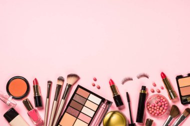 Pembe arka planda profesyonel makyaj malzemeleri.