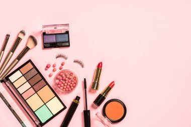 Pembe arka planda profesyonel makyaj malzemeleri.