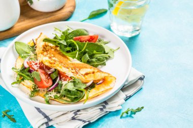 Beyaz tabakta yeşil yapraklı omlet..