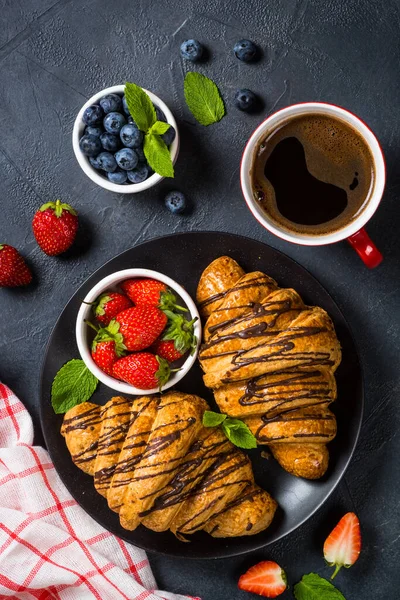 Croissant con bacche fresche e tazza di caffè su nero. — Foto Stock