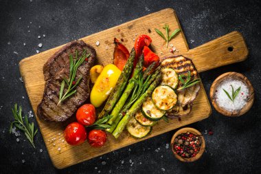 Sığır eti biftek siyah taş masada sebze ile ızgara.