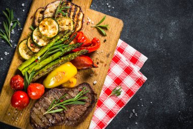 Sığır eti biftek siyah taş masada sebze ile ızgara.