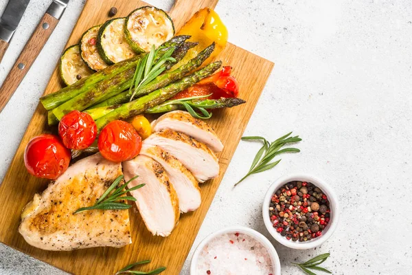 Pechuga de pollo asada con verduras en una tabla de servir de madera. —  Fotos de Stock