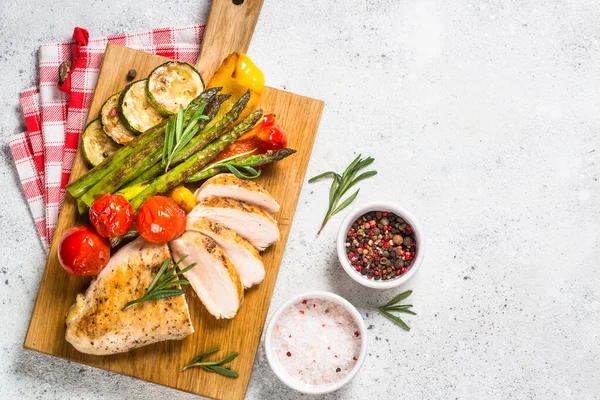 Chicken breast grilled with vegetables on a wooden serving board. — Stock Photo, Image