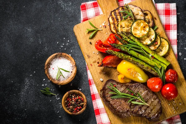 Marha steak grillezett zöldségekkel, fekete kőasztal. — Stock Fotó