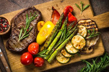 Sığır eti biftek siyah taş masada sebze ile ızgara.