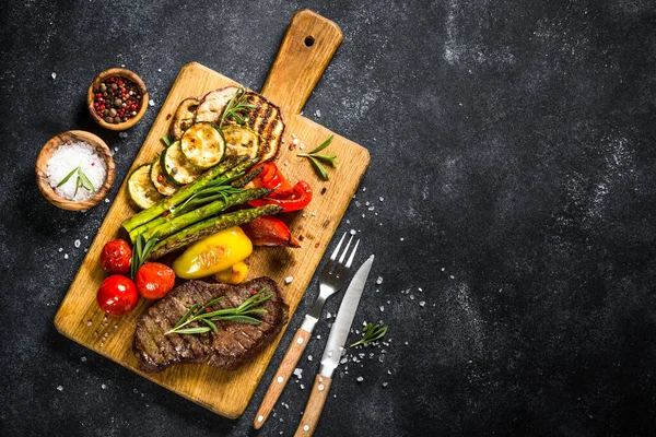 Carne de res asada a la parrilla con verduras en mesa de piedra negra . —  Fotos de Stock