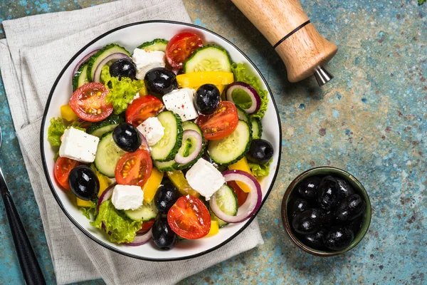 Görög saláta fekete tányéron az asztalon. — Stock Fotó
