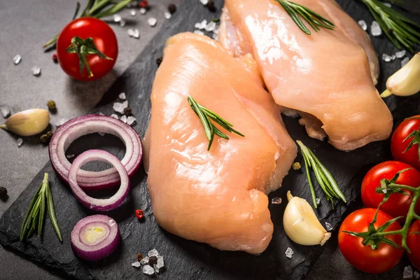 Hühnerfilet mit Gewürzen am schwarzen Tisch. — Stockfoto