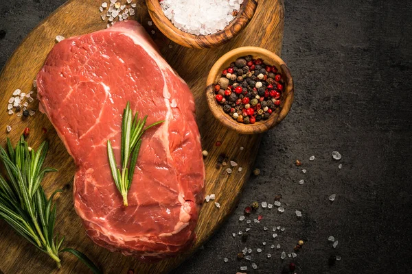 Bife de vaca fresco na mesa preta. — Fotografia de Stock