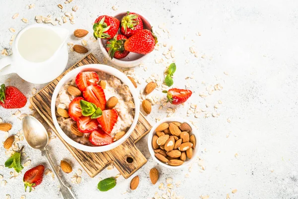 Bubur oatmeal dengan stroberi segar dan kacang pada latar belakang putih. — Stok Foto